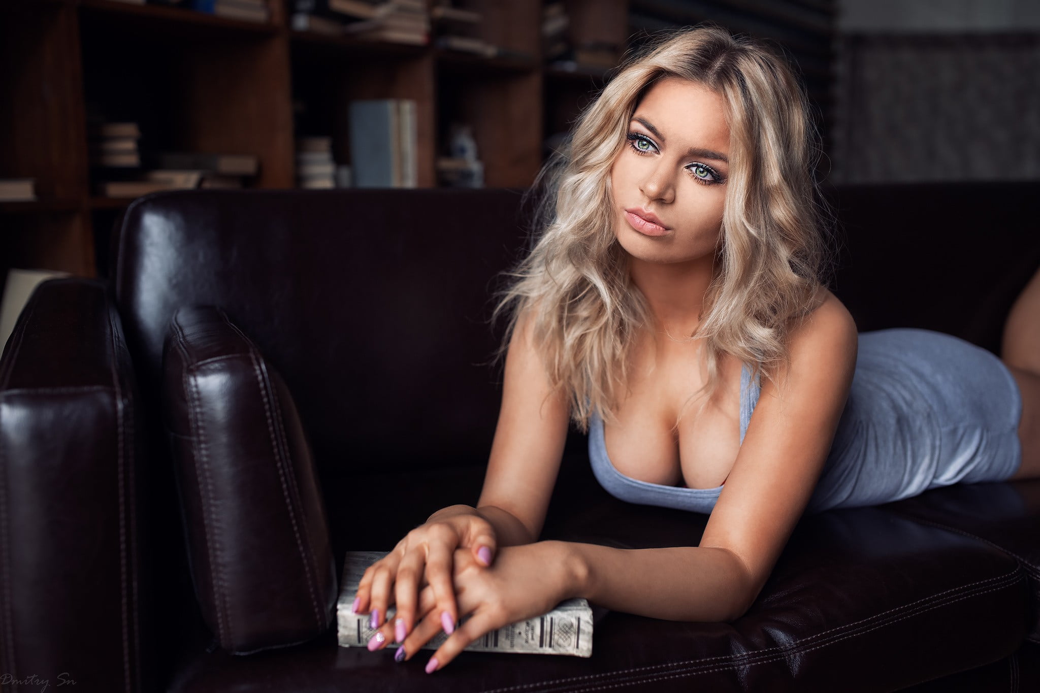 Блондинка с длинными волосами сидит на диване в сетчатом наряде