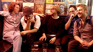 group of five men sitting together on black sofa