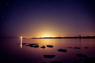 silhouette of rocks on water during golden hour HD wallpaper