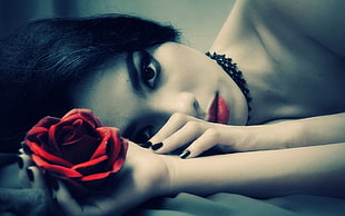 closeup photography of woman laying holding fully bloomed red rose flower HD wallpaper