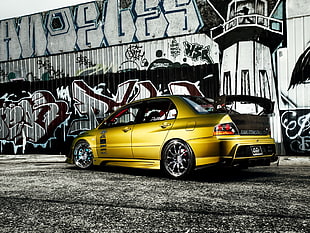 gold and black sports sedan near graffiti printed wall