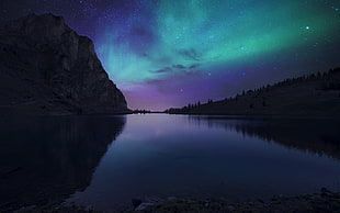 large body of water beside mountain during nighttime HD wallpaper