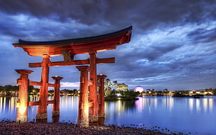 lighted brown wooden stand near body of water during night time