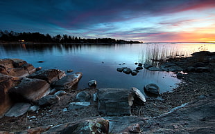 landscape photograph of rocks at lakeside during golden hour HD wallpaper
