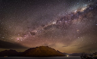 mountain on body of water under clustered star during night time