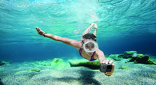 woman swimming underwater holding gray action camera HD wallpaper