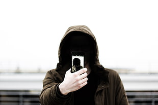 person wearing brown hoodie taking a Selfie during cloudy day HD wallpaper