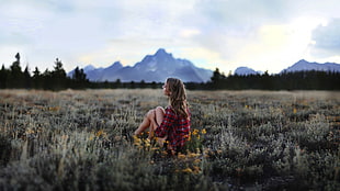 woman wearing red dress sitting on green grass during daytime