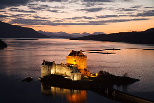 landscape photo of a lighted house near mountain under blue skie, eilean donan castle, skye