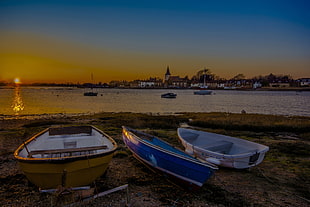 three white and blue wooden boats in sea shore