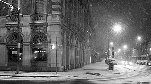 snowed street with open street lights between concrete buildings