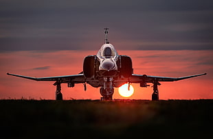 silver airplane on runway during sunset