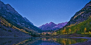 mountains with trees near body of water