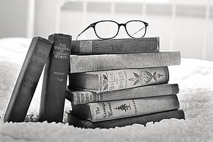 pile of books and eyeglasses on the top of it grayscale photo HD wallpaper