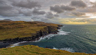 green cliff near shore during golden hour