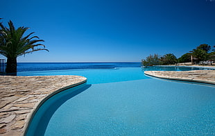 photography of clear pool near seashore at broad daylight HD wallpaper