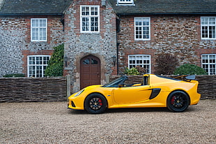 yellow convertible sports car parked beside brown brick building