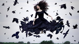 woman in black long-sleeved dress fly with flock of crow