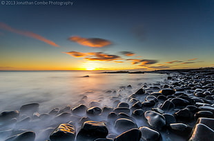 fog covered rock formation on seashore during sunset