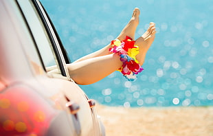 person with multicolored petaled flower anklet lying inside vehicle near sea HD wallpaper