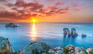 body of water near rocks during sunset