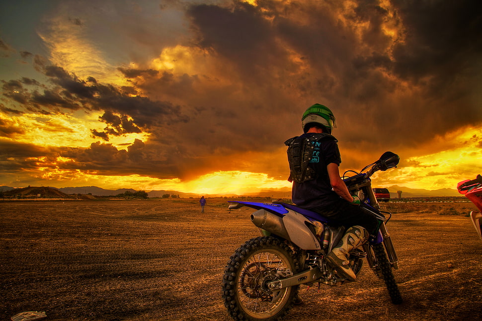 Photo of man riding motocross dirt bike under nimbus clouds HD ...