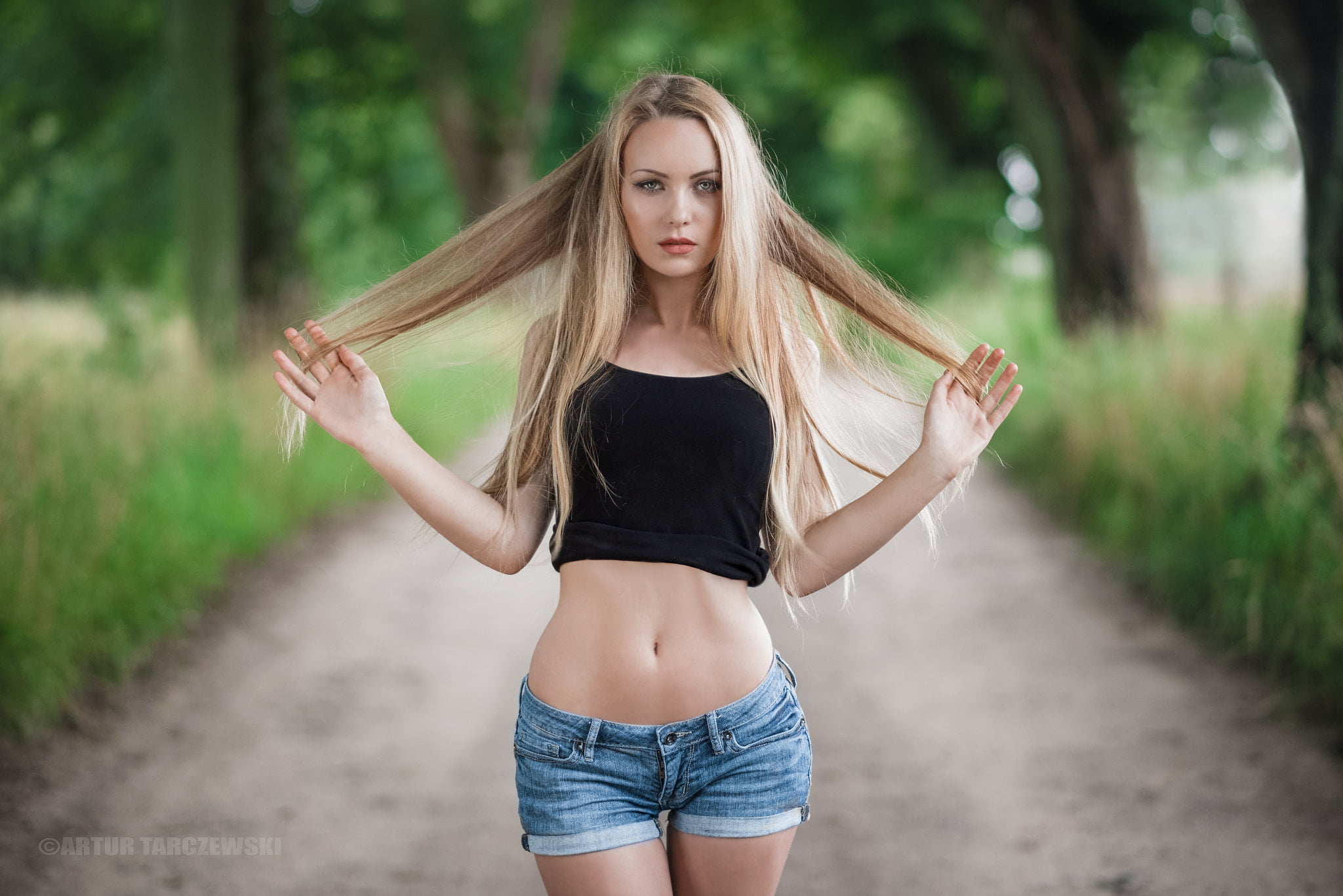 Blonde with long hair puts on denim shorts. A - Stock Photo