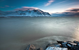 mountain covered with snow near body of water