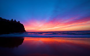 silhouette photography of cliff near body of water during sunset