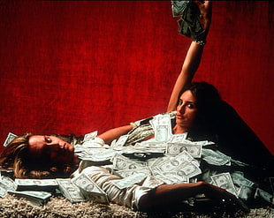 woman and man lying on fleece textile while covered with US dollar bills HD wallpaper