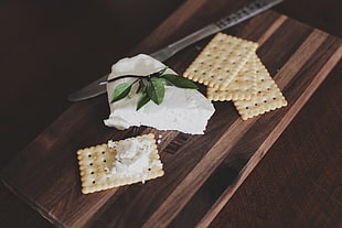four rectangular soda crackers and white cheese on brown wooden board HD wallpaper