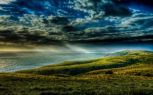 mountain near body of water under white clouds