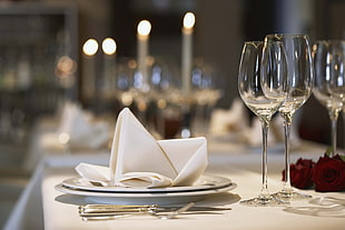 selective focus photography of white table napkin on white ceramic plate near wine glasses HD wallpaper