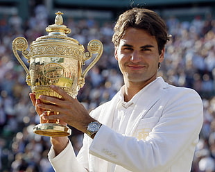 man in white polo shirt holding brass-colored trophy during daytime