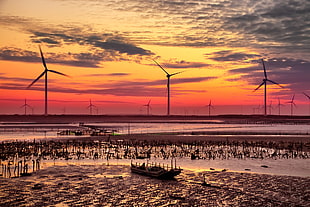 silhouette of windmills near body of water