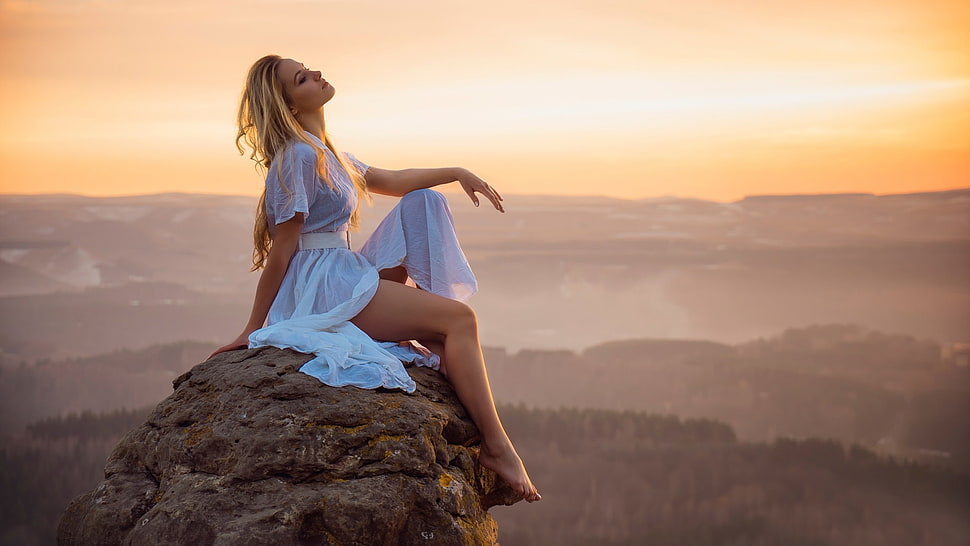 woman wearing white dress sitting on rock formation during golden hour HD wallpaper