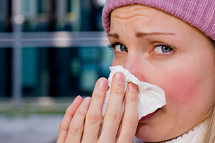 woman blowing nose on white tissue paper