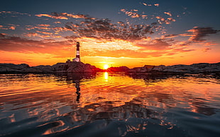 white and black light house at golden hour, lighthouse, water, sunset, clouds