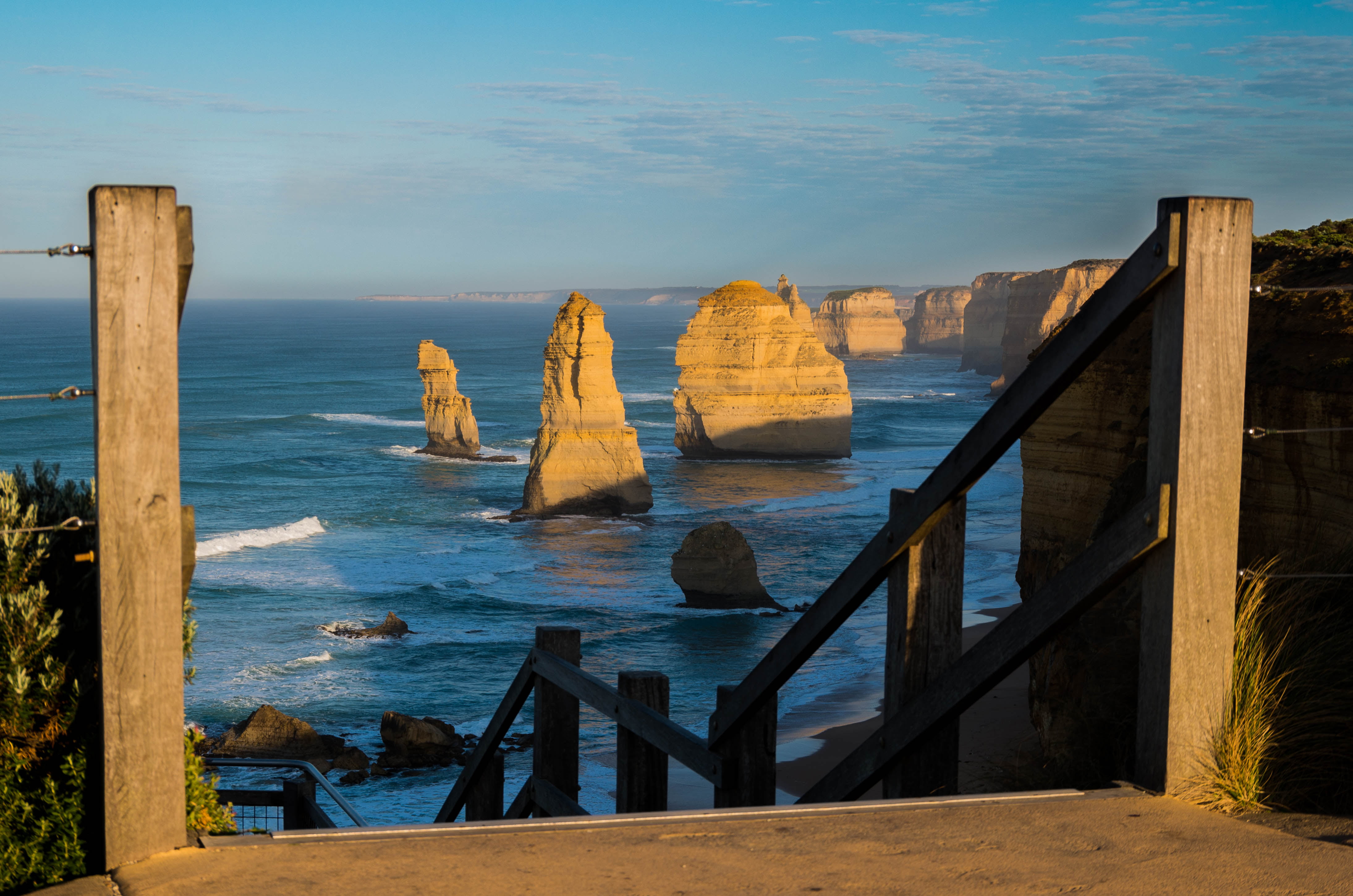 brown wooden balustrade in distant of rocks on sea