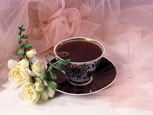 white-green-and-red ceramic tea cup with saucer set on white chiffon surface