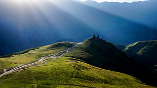 photo of sun ray on green grass field and mountain