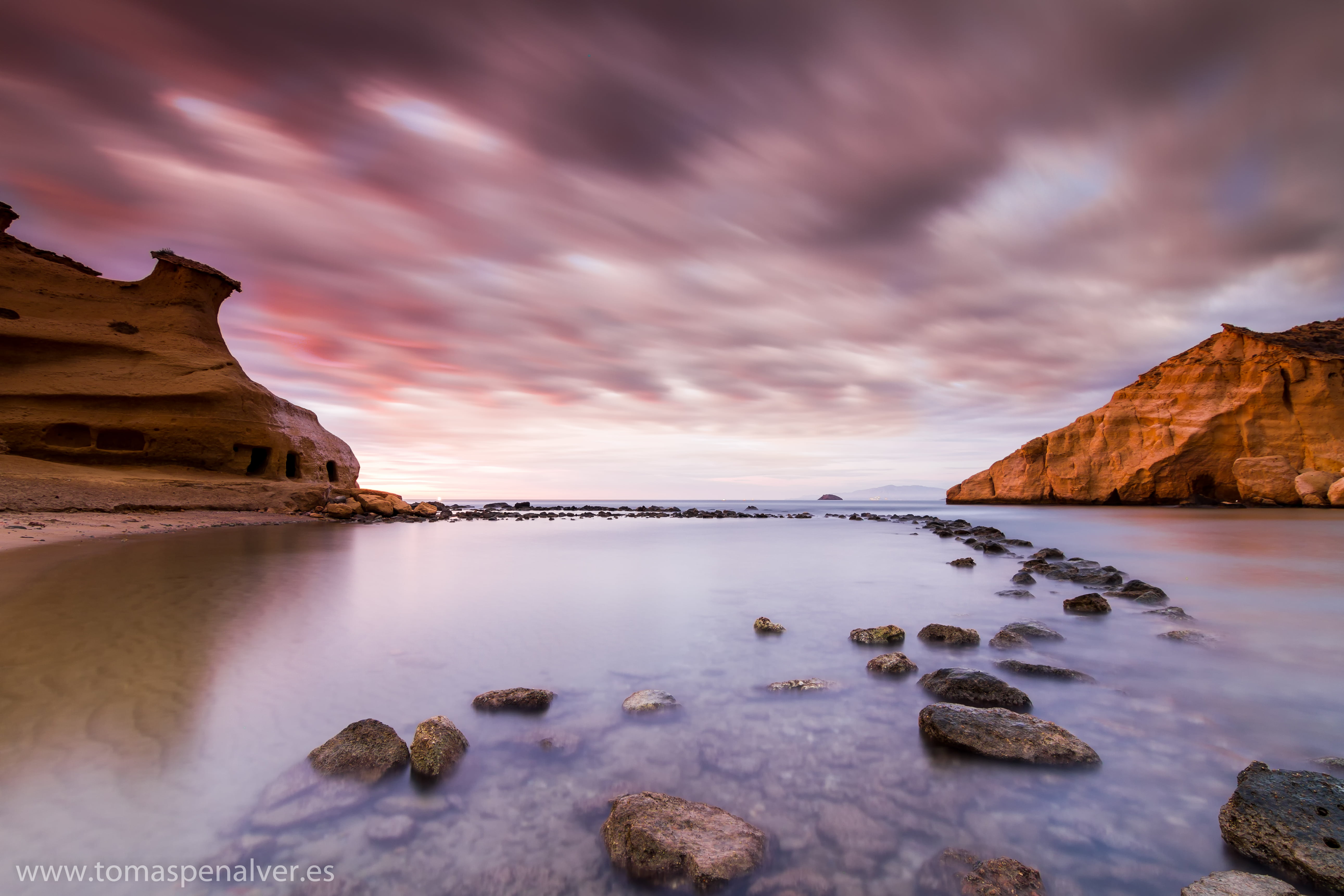 timelapse photography of a body of water near rock mountains under cloudy sky