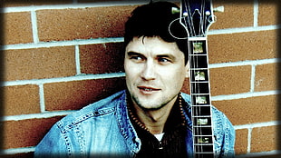 man in blue denim jacket holding black guitar HD wallpaper