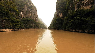 large body of water beside mountains during daytime HD wallpaper