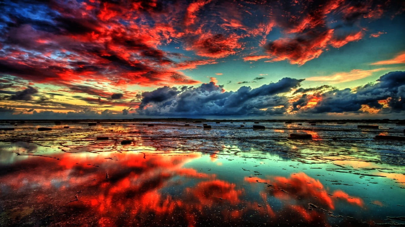 landscape photography of calm body of water under orange cloud blue skies