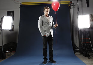 man in gray notch-lapel blazer and black pants holding red balloon HD wallpaper