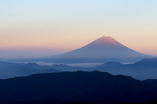 photography of mountain covered by fog during sunrise