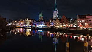 lightened city buildings near body of water during nighttime