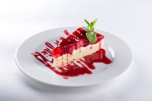 sliced cheesecake topped with strawberry syrup on round white ceramic saucer HD wallpaper