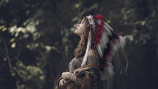 woman in white, red, and black feather headdress looking up HD wallpaper